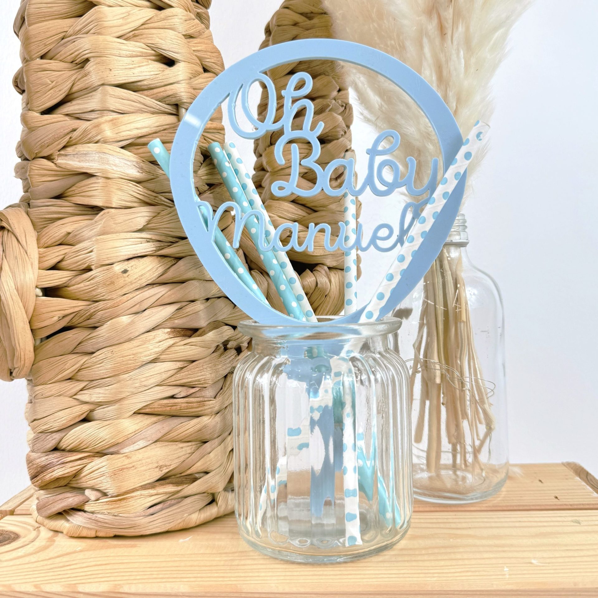 Imagen de un topper metido en un vaso de cristal, personalizado en madera con el texto "oh baby manuel"